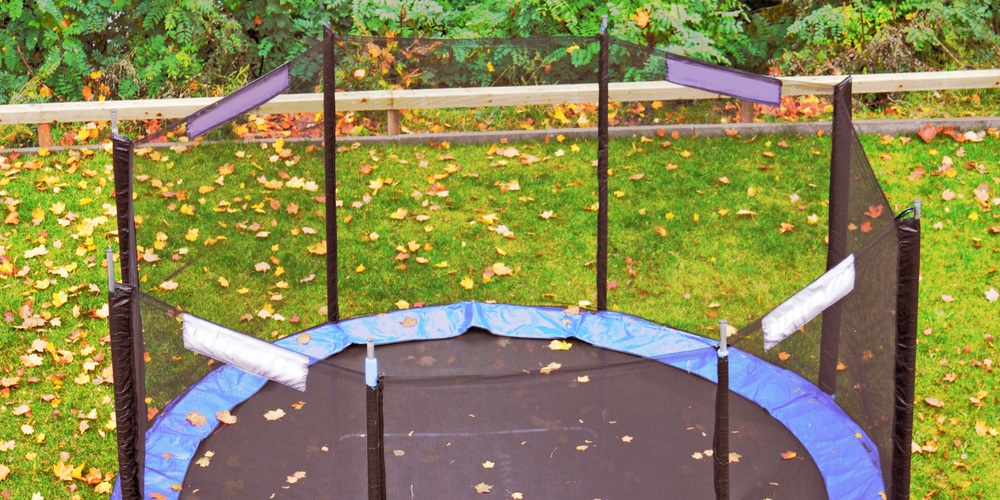 Trampoline covered in leaves in a backyard